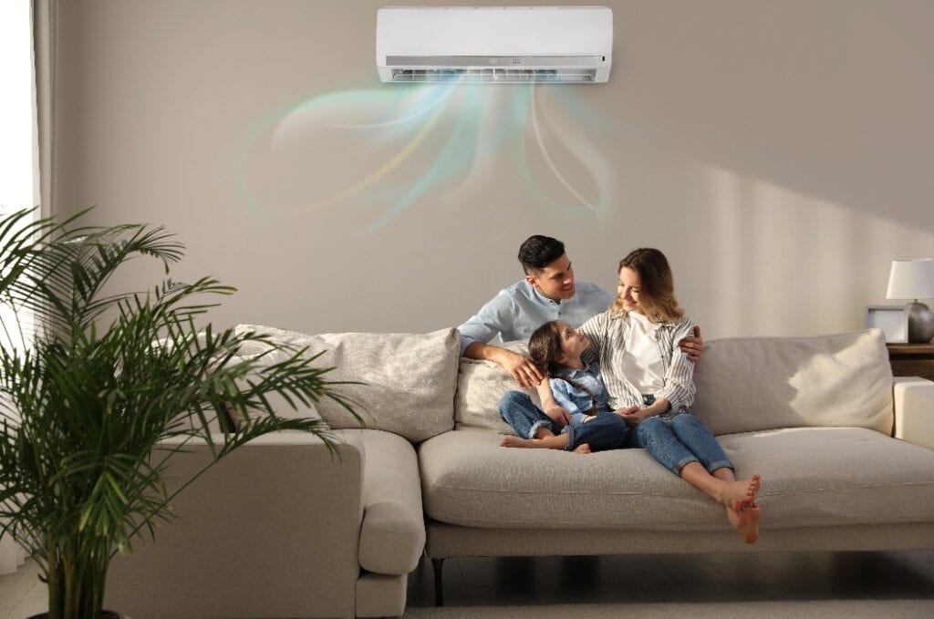 Happy family resting under air conditioner on beige wall at home