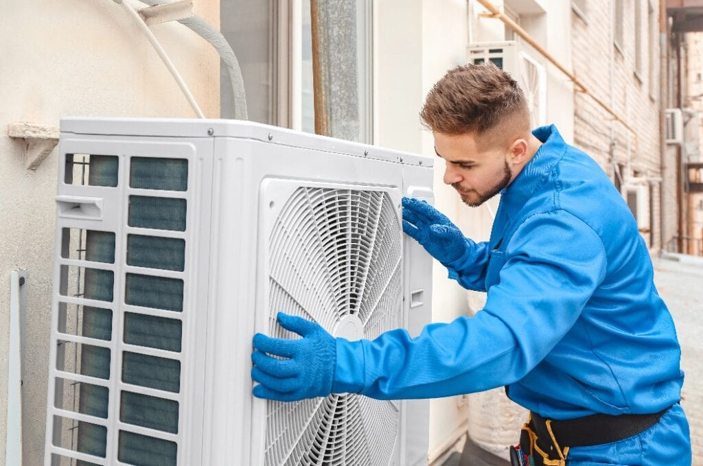 Male technician installing outdoor unit of air conditioner